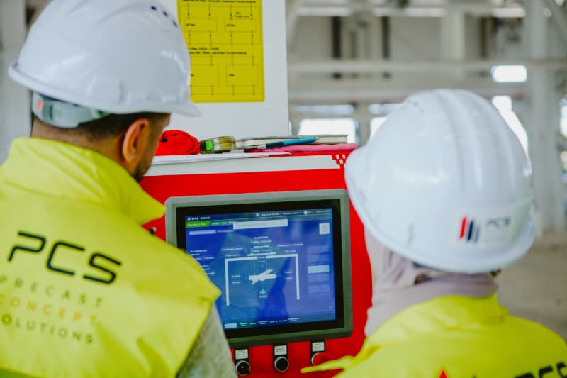 Two PCS workers following process of fabrication on computer screen.